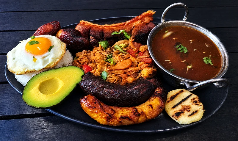 Bandeja paisa: beans, rice, chicharron, pulled meat, chorizo, fried egg, avocado and arepa on one platter