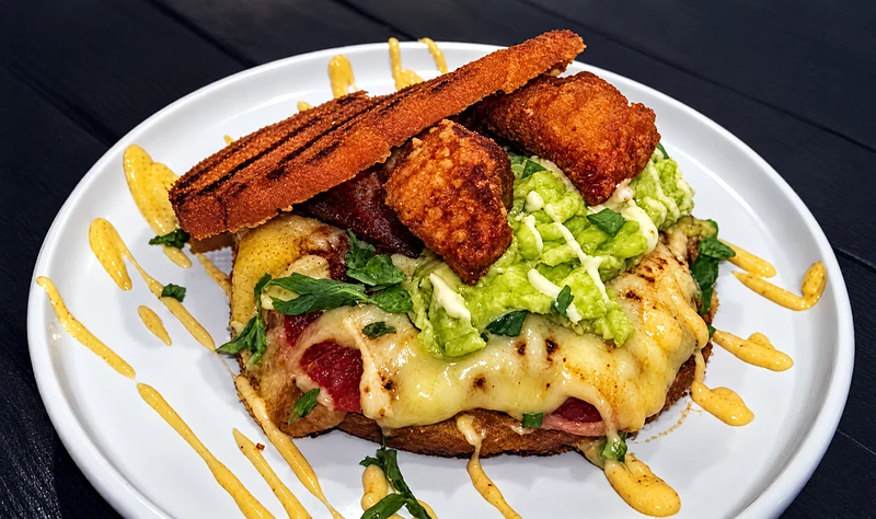 Chancho Chicharron arepa topped with crisp chicharron, guacamole and cheese