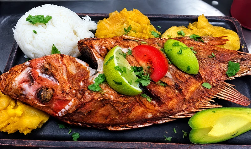 Whole deep-fried red snapper with rice, patacones, tomato, lime and avocado