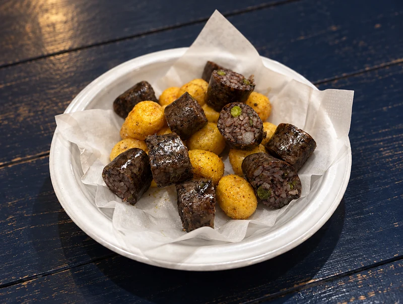 Sliced morcilla rellena with golden papa criolla in a paper-lined bowl