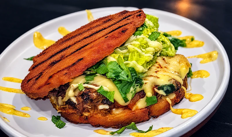 Toro arepa: a grilled arepa over pulled beef, guacamole, melted cheese and mayonnaise